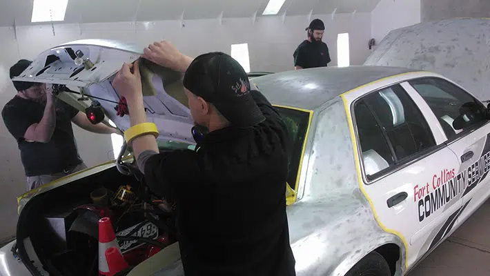 A group of auto technicians working on a taxi fleet repair.