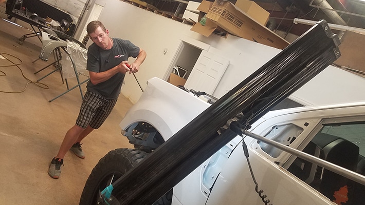 An auto technician performing a auto repair on a white truck.