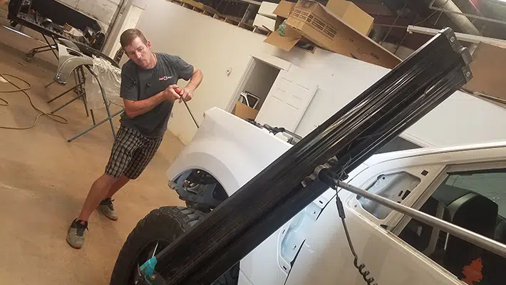 An auto technician performing a auto repair on a white truck.